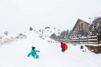 Garçon et fille descendant une colline en traîneau à neige — Photo de stock