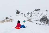 Irmãos felizes trenó para baixo colina no inverno — Fotografia de Stock