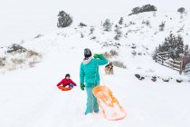 Glückliche Geschwister rodeln im Winter den Berg hinunter — Stockfoto