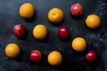 High angle close up of red apples and oranges on black background. — Stock Photo