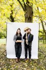Portrait of woman and bearded man holding wooden blocks standing in front of white background in a garden, looking at camera. — Stock Photo