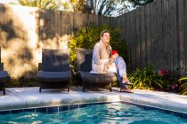Жінка сидить на шезлонгу біля басейну — стокове фото