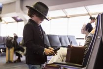 6-річний хлопчик дивиться на свій портфель в аеропорту — стокове фото