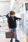 6-летний мальчик смотрит на часы в аэропорту — стоковое фото