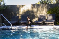6-jähriger Junge mit schwarzem Anzug und Fliege steht am Pool — Stockfoto