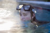 Дівчина-підліток у басейні в окулярах, піднімається пара — стокове фото
