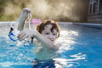Menino de seis anos jogando em uma piscina quente, vapor subindo. — Fotografia de Stock