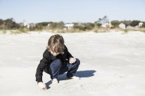 6-jähriger Junge zeichnet im weichen weißen Sand am Strand — Stockfoto