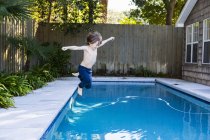 Niño de seis años que salta a la piscina. - foto de stock