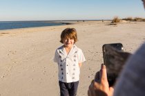 Ein sechsjähriger Junge wird von seiner Mutter am Strand fotografiert — Stockfoto