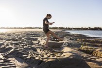 Девочка-подросток, играющая в песчаных дюнах, на пляже — стоковое фото