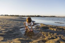 Ragazzo di sei anni che gioca sulla spiaggia in una piscina d'acqua — Foto stock
