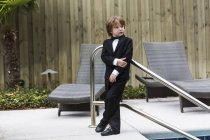 6 anos de idade menino vestindo traje formal de pé ao lado da piscina — Fotografia de Stock