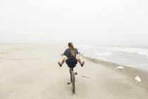 Une adolescente monte une bicyclette sur du sable à la plage, île Saint-Simon Géorgie — Photo de stock
