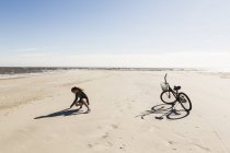 Teenager-Mädchen an einem weiten, leeren Sandstrand beim Muschelsammeln. — Stockfoto