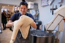 Femme portant un tablier debout dans une boulangerie artisanale, travaillant avec du levain . — Photo de stock