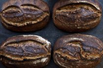 Grand angle gros plan de quatre pains fraîchement cuits dans une boulangerie artisanale . — Photo de stock