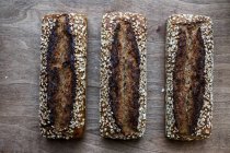 High angle close up of three freshly baked seeded loaves of bread in an artisan bakery. — Stock Photo