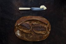Pan recién horneado en una panadería artesanal con un cuchillo y una porción de mantequilla . - foto de stock