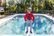 6 anos de idade menino de pé na placa de mergulho com vista para a piscina — Fotografia de Stock