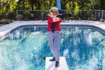 6-jähriger Junge steht auf Sprungbrett mit Blick auf Pool — Stockfoto