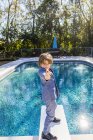 Garçon de 6 ans debout sur un plongeoir surplombant la piscine — Photo de stock
