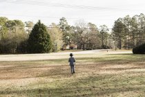 Вид сзади на мальчика в костюме, идущего по газону — стоковое фото