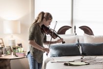 Chica de 13 años tocando el violín en el dormitorio - foto de stock