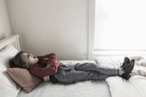 6 anno vecchio ragazzo riposo su suo letto — Foto stock