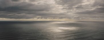 Бурхливі хмари пролітають над безкраїм океаном, просочуючи сонячне світло на воду, на північному узбережжі штату Орегон. — стокове фото