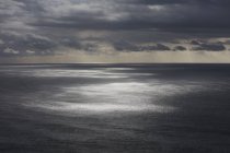 Бурхливі хмари пролітають над безкраїм океаном, просочуючи сонячне світло на воду, на північному узбережжі штату Орегон. — стокове фото