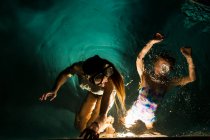 Due bambini che nuotano in piscina di notte — Foto stock