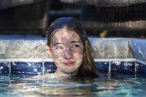 13 anno vecchio ragazza in piscina con riflessioni giocare su suo faccia — Foto stock