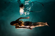 Dos niños nadando en la piscina por la noche - foto de stock