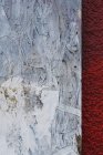 Painted white particle board against red stucco — Stock Photo