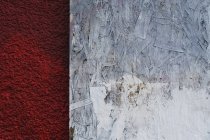 Painted white particle board against red stucco — Stock Photo