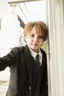 Portrait of 6 year old boy opening a door — Stock Photo