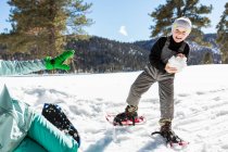 Menino de seis anos com sapatos de neve segurando uma grande bola de neve . — Fotografia de Stock