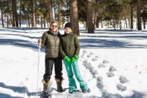 Adult woman and teenage girl in snow shoes in woodland holding ski poles — Stock Photo