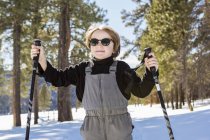 Menino de seis anos na floresta segurando bastões de esqui — Fotografia de Stock