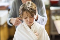 Cropped shot of mother cutting hair to adorable son at home — Stock Photo