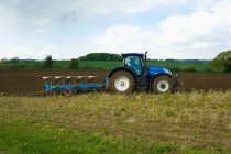 Вид сбоку на боронование трактора, вспашка в щетине в поле . — стоковое фото