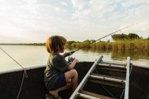 Um menino de cinco anos pescando de um barco no rio Zambeze, Botsuana — Fotografia de Stock