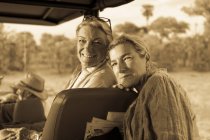 Senior woman and mature daughter, two generations of women in a safari vehicle laughing. — Stock Photo