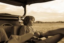 Fünfjähriger Junge sitzt in einem Safari-Fahrzeug, einfarbig. — Stockfoto