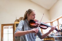 13-летняя девочка играет дома на скрипке — стоковое фото