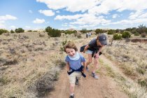 6 year old boy running on hiking trail with older sister, Galisteo Basin, NM. — Stock Photo