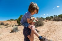 14 year old girl giving younger brother a piggyback ride, Galisteo Basin, NM. — Stock Photo