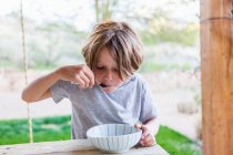 6 anos de idade menino comer arroz em seu pátio — Fotografia de Stock