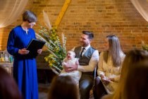 Zelebrant führt Taufzeremonie für Eltern und ihre kleine Tochter in historischer Scheune durch. — Stockfoto